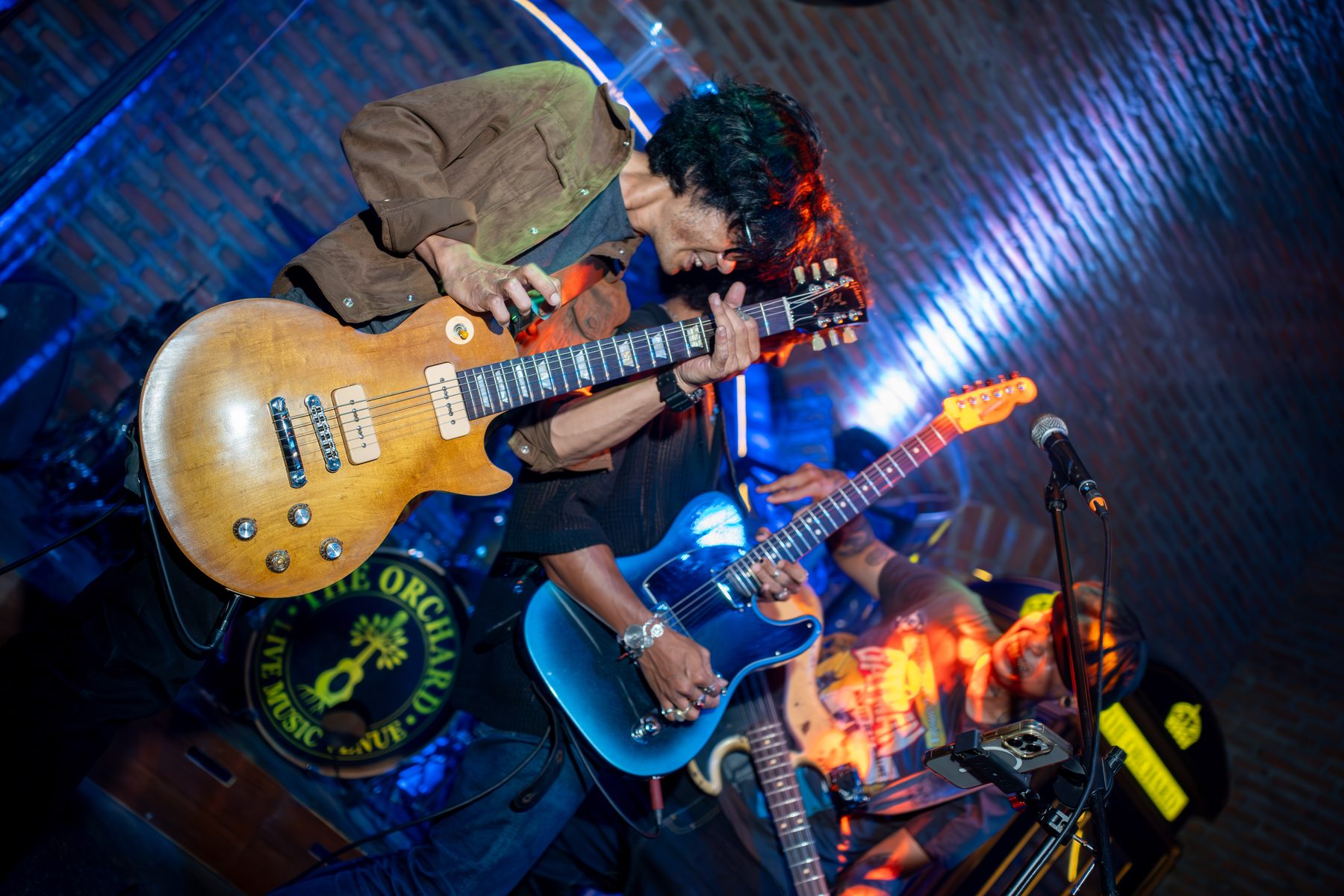 Guitarists performing live on stage at The Orchard